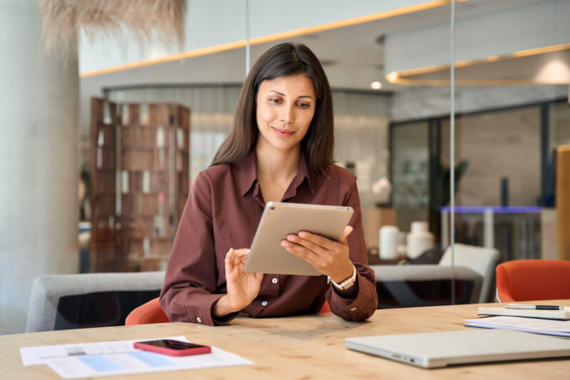 Woman sitting at desk using tablet and AI