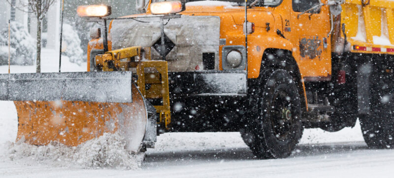 Close up of yellow blade of a yellow snowplow during a snow storm