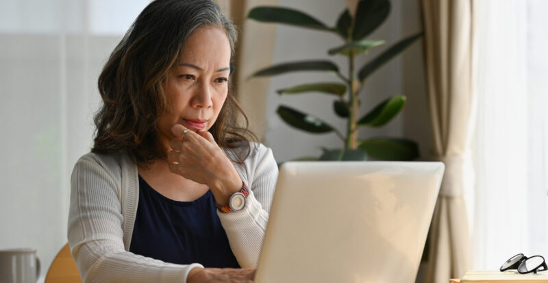 Old woman work at home using notebook computer.