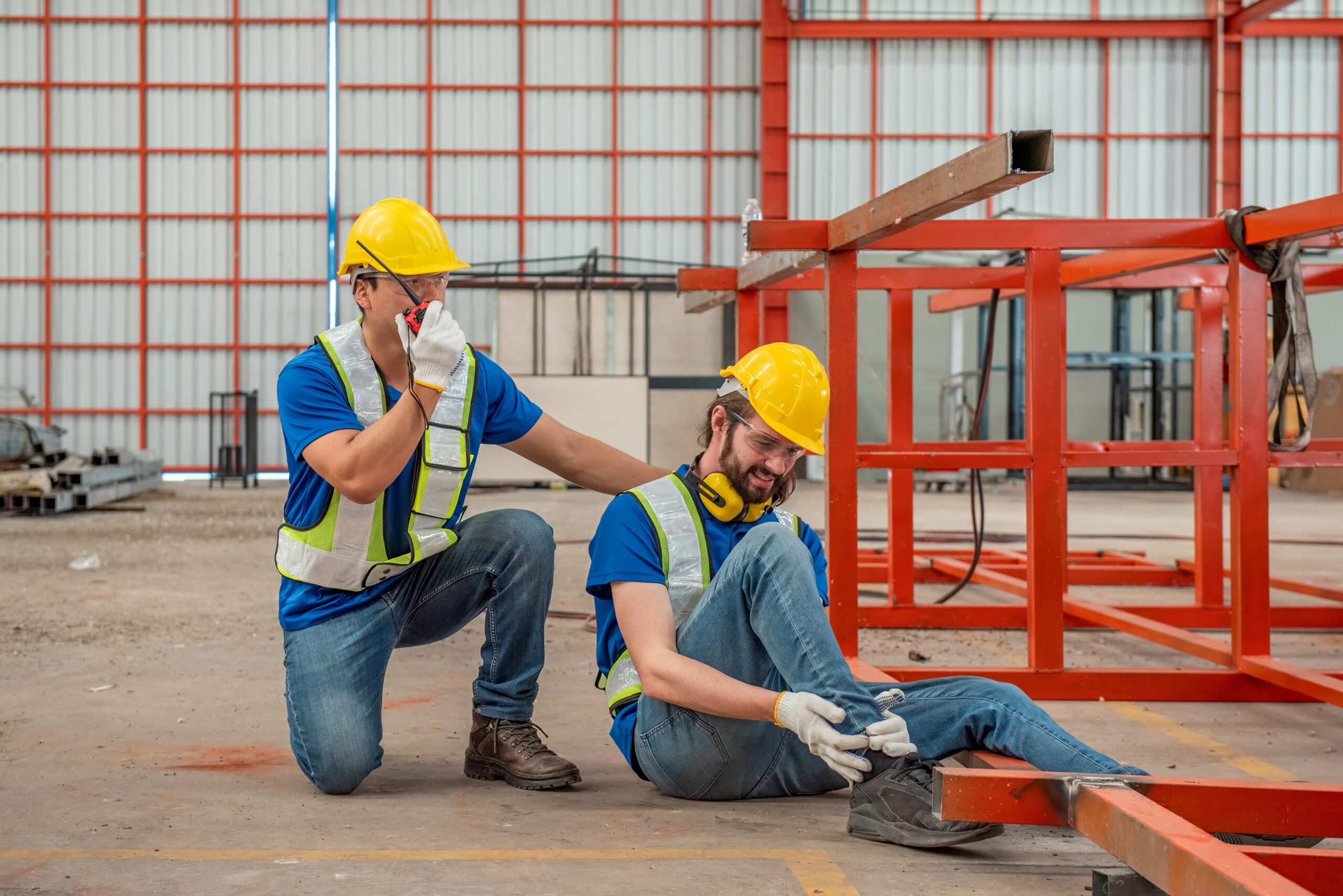 A worker is injured at a construction site and his coworker is calling for help.