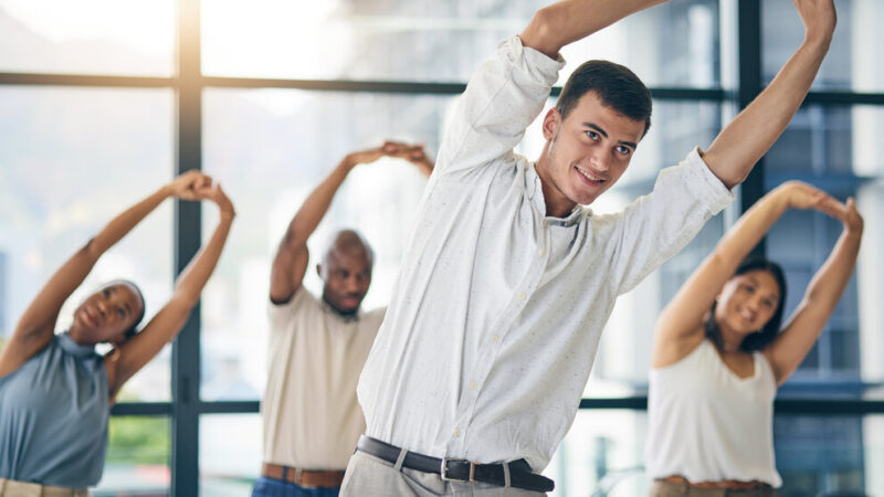 Team building, stretching and a team of business people in the office to workout for health or mobility together. Exercise, fitness and training with an employee group in the workplace for a warm up