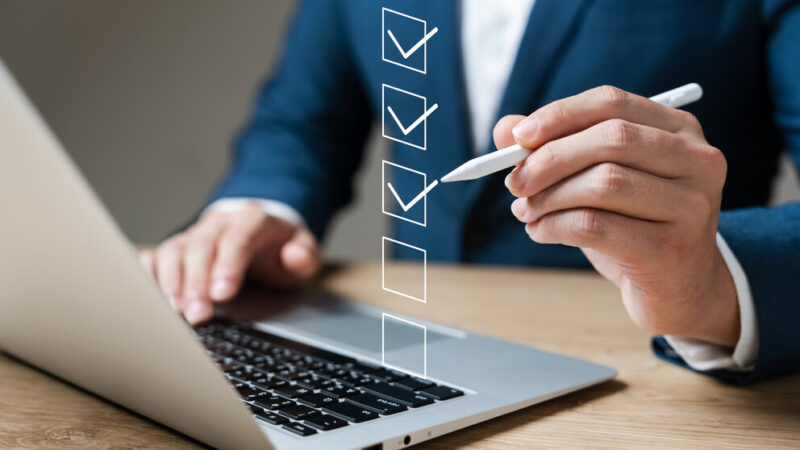 Business performance checklist concept, businessman using laptop doing online checklist survey, filling out digital form checklist.