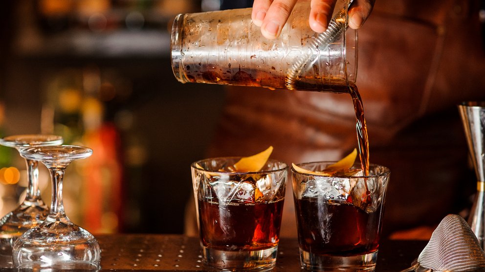 Bartender pouring alcoholic drink into the glasses