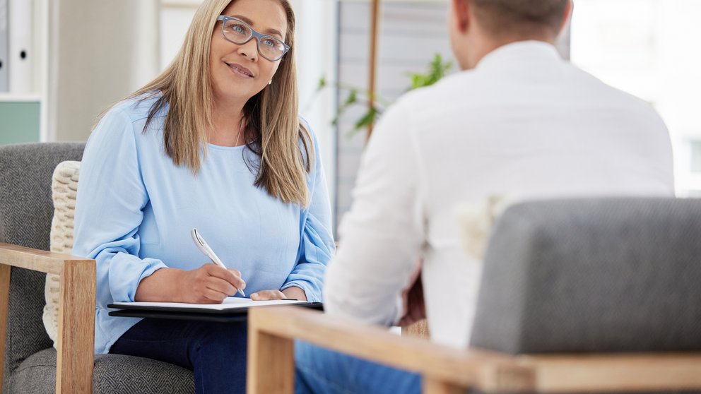 Shot of a mature psychiatrist sitting with her patient during a consultation in her clinic. This can help your employees with their mental health.