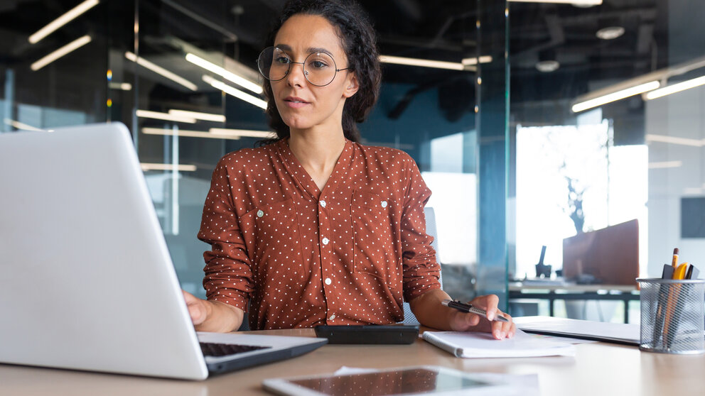 Successful satisfied and happy business woman working inside modern office, hispanic woman in glasses and shirt using laptop at work