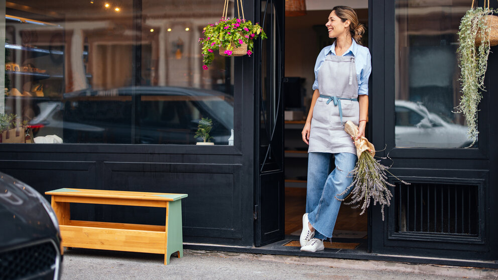 Portrait Of A Successful Small Business Owner Holding Flowers And Standing At Bakery Entrance