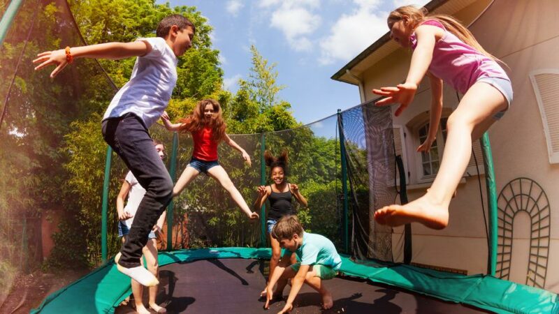 Happy friends jumping on the trampoline in summer