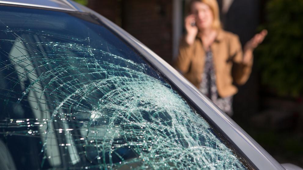 Woman Phoning For Help After Car Windshield Has Broken