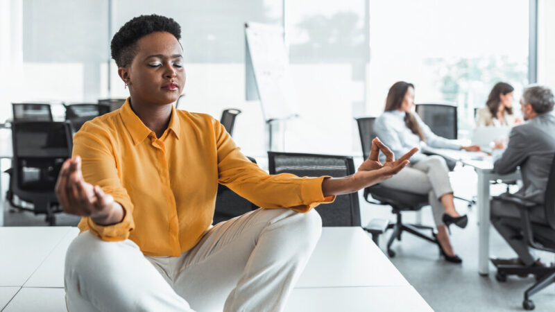 Young black female relax practice yoga at workplace, breathe fresh air. Peace concept.