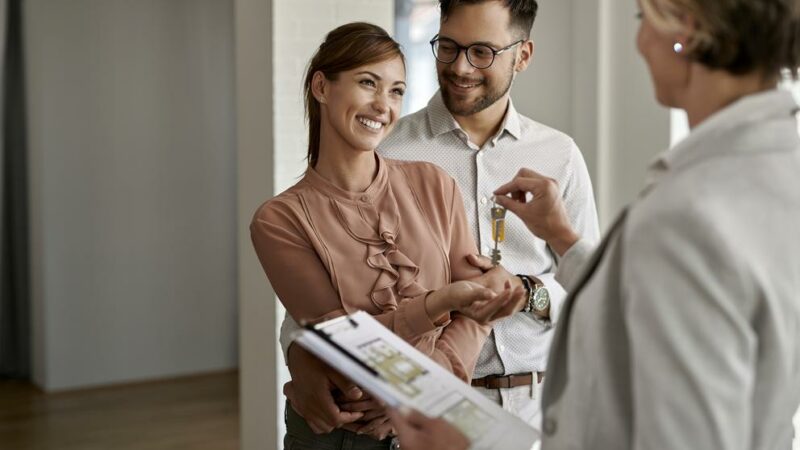 Happy couple receiving keys to their condo, and learning about the importance of insuring it