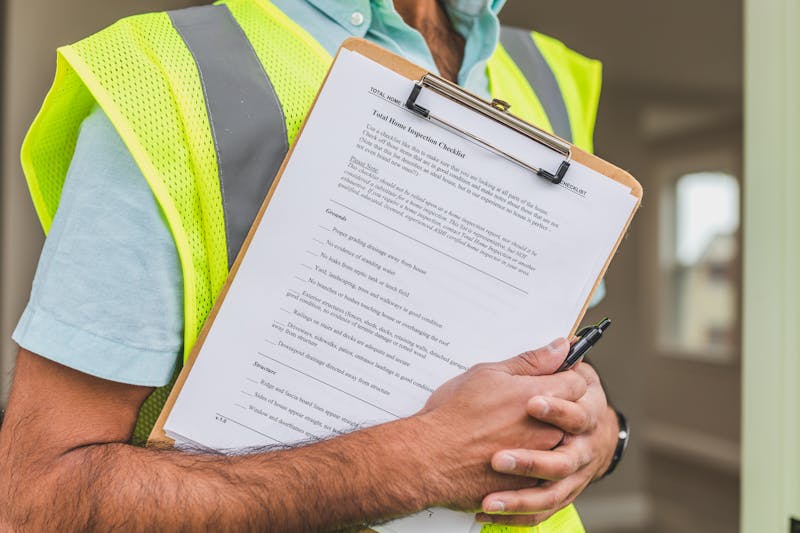 Person in Yellow Reflective Safety Vest Holding a Pen and workplace first aid checklist