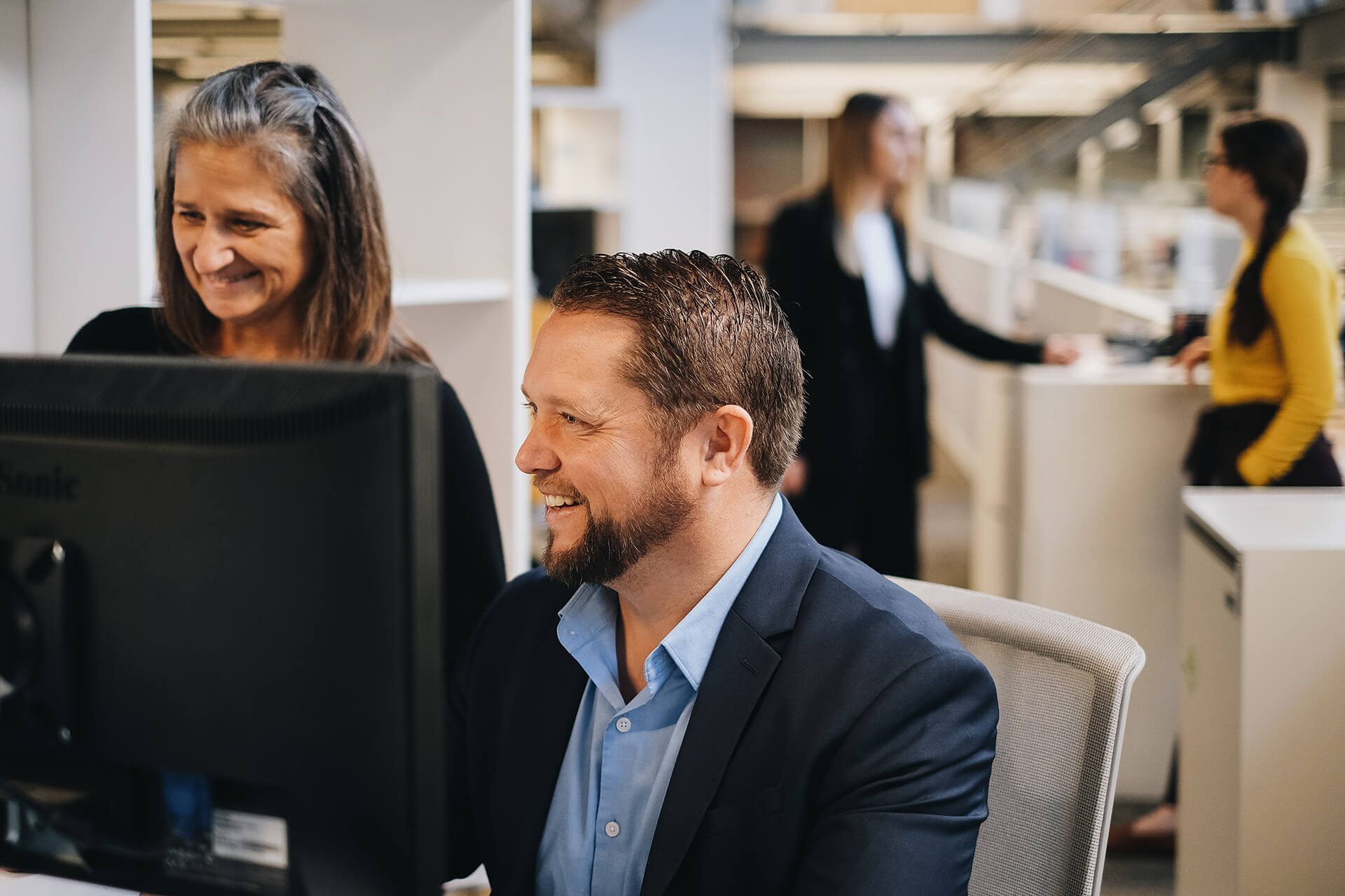 smiling man and woman looking at computer